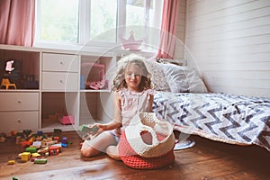 child girl cleaning her room and organize wooden toys into knitted storage bag