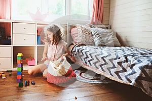 Child girl cleaning her room and organize wooden toys into knitted storage bag