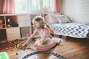 Child girl cleaning her room and organize wooden toys into knitted storage bag