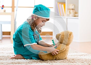 Child girl with clothes of doctor playing plush toy
