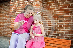 Child girl with cochlear implant with her mother spend time outdoor. Hear impairment and deaf community concept. Deaf