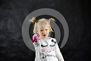 Child girl conjures a magic wand on a black background photo