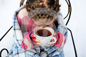 Child girl with a cup of hot tea outdoors