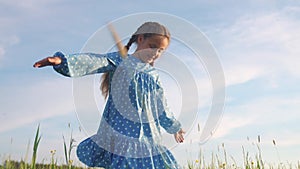 child girl a dancing in the field park. happy childhood family friendship concept. girl kid whirls in a blue dress in