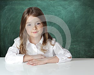 Child girl at desk chalk board background.