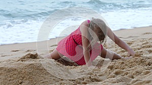 Child girl dig and play in sand on seashore
