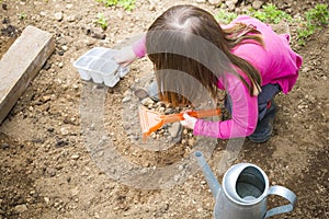 Child girl digging soil for cultivating the garden