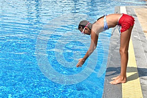 Child girl dives into the pool. Girl learning to swim autdoor. Swimming pool in the hotel. Children swim in the outdoor pool.