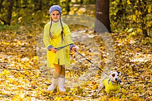 Child girl with dog outdoors. Kid with pet at autumn. Jack russell terrier puppy.