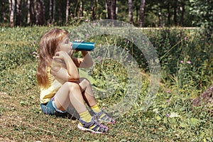 child girl drinking Pepsi Cola from an iron can outdoor