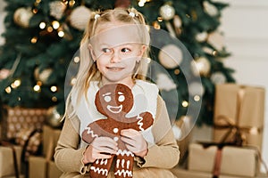 Child girl eating iced sugar cookies under Christmas tree Waiting for Christmas.