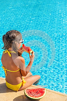Child girl eats watermelon near the pool. Selective focus.