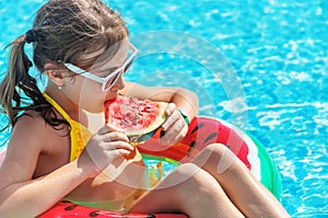 Child girl eats watermelon near the pool. Selective focus.