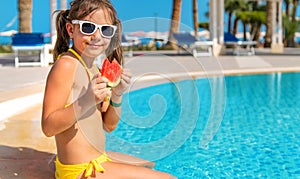 Child girl eats watermelon near the pool. Selective focus.