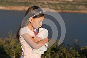 Child girl is embracing soft toy bear.