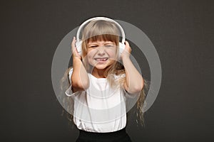 child girl enjoys music in her big white headphones and smile.Blue eyes blonde hair girl listen to music