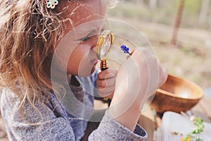 Child girl exploring nature in early spring forest. Kids learning to love nature. Teaching children about seasons changing.