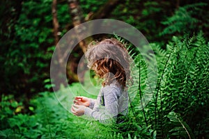 Child girl exploring nature in summer forest