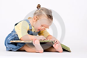 Child girl with glasses reading book on white.