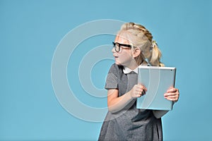 Child girl in glasses violated parental control and is playing a tablet computer