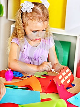 Child girl glue in preschool.