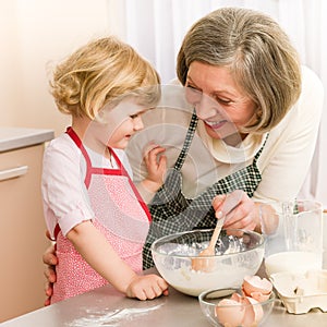 Child girl and grandmother baking cake