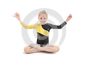 Child girl gymnast sitting in yoga position isolated on white