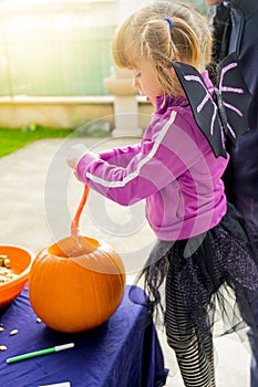 Child girl in halloween bat costume, carving pumpkins on Halloween day