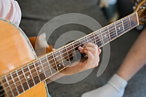 Child girl hand playing guitar in room - leisure music and hobby concept