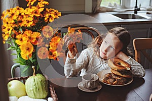 Child girl having breakfast at home in autumn morning. Real life cozy modern interior in country house