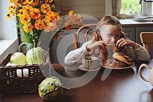 Child girl having breakfast at home in autumn morning. Real life cozy modern interior in country house