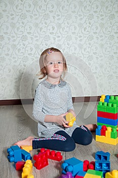 Child girl having fun and build of bright plastic construction blocks