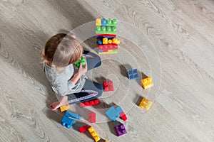 Child girl having fun and build of bright plastic construction blocks