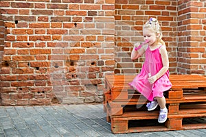 Child girl with hearing aid cochlear implant in pink dress having fun on summer street. Aid for the treatment of