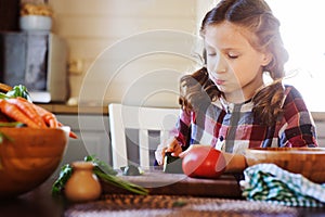 Child girl helps mom to cook and cut fresh vegetables for salad with knife