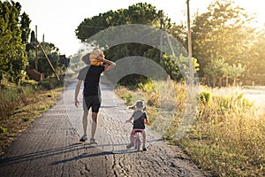 Child girl with her father carrying a pumpkin on a country road