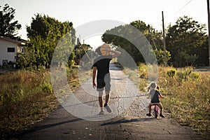 Child girl with her father carrying a pumpkin on a country road