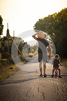Child girl with her father carrying a pumpkin on a country road. Vertical