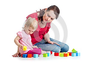 Child girl and her mom play with building blocks