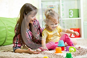 Child girl and her mother playing together with toys