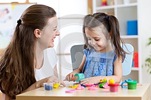 Child girl with her mother sculpts from clay