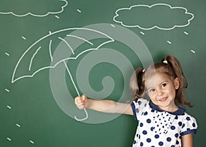 Child girl hold umbrella near school blackboard, weather concept