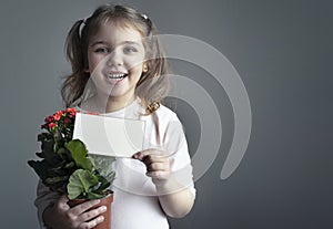 Child girl holding paper card portrait. Little kid with flower pot showing informatrion poster. Mother\'s day,holiday