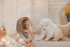 Child girl is holding puppy on her hands near pink the gift boxes