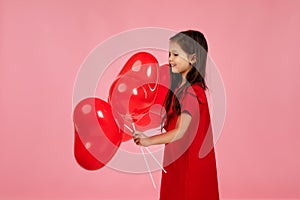 Child girl holding red heart shaped balloon