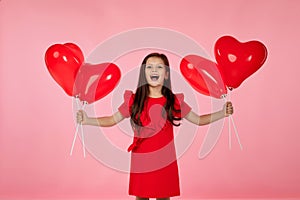 Child girl holding red heart shaped balloon
