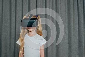 child girl at home in virtual reality VR glasses watching video, playing games. modern children are well versed in photo