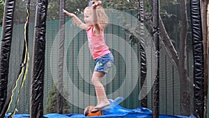 Child girl jumping on a trampoline and playing in a country house. Games for children.