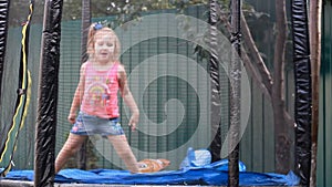 Child girl jumping on a trampoline and playing in a country house. Games for children.