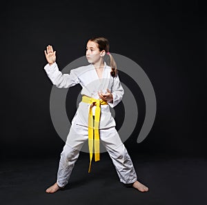 Child girl in karate suit with yellow belt show stance